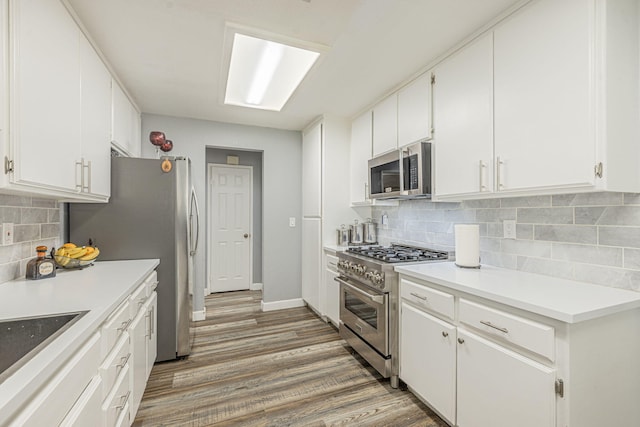 kitchen with white cabinets, backsplash, stainless steel appliances, and light hardwood / wood-style flooring