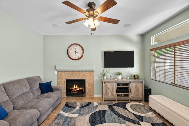 tiled living room featuring a tiled fireplace and ceiling fan