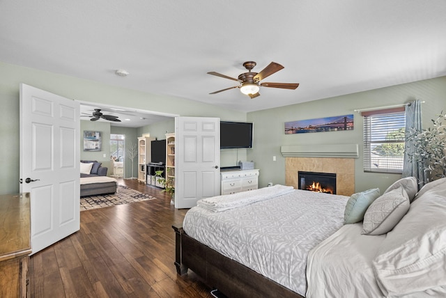 bedroom featuring a tile fireplace, ceiling fan, and dark hardwood / wood-style floors