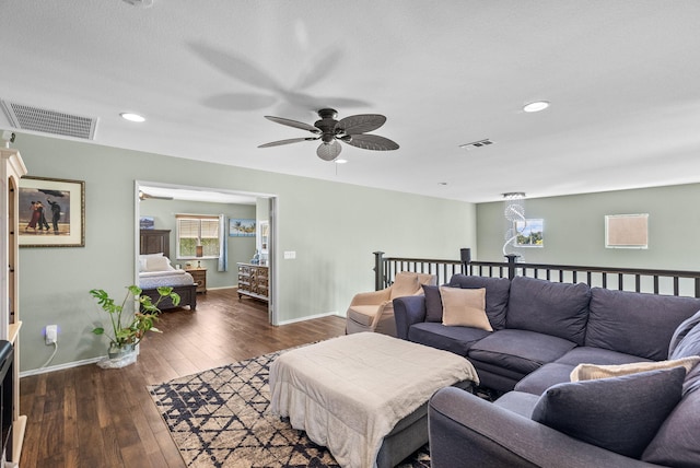 living room with a textured ceiling, ceiling fan, and dark wood-type flooring