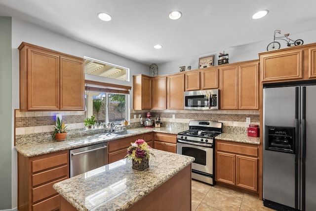 kitchen with appliances with stainless steel finishes, tasteful backsplash, light stone counters, and sink