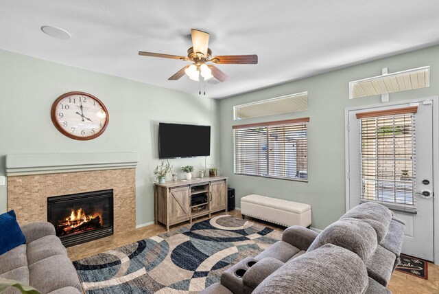 living room with ceiling fan, light tile patterned floors, and a tiled fireplace