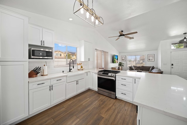 kitchen with lofted ceiling, a sink, stainless steel appliances, a peninsula, and a ceiling fan