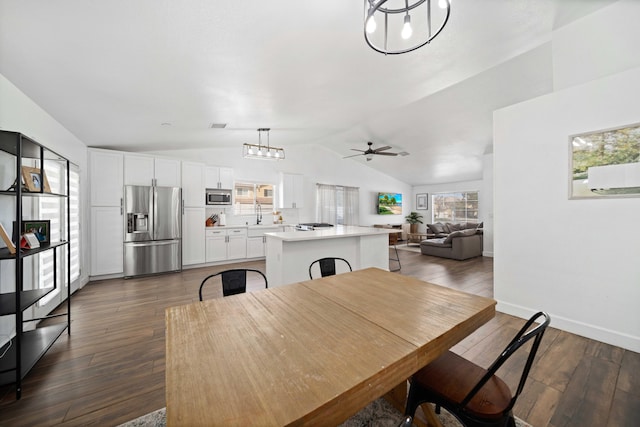 dining area featuring dark wood-type flooring, baseboards, vaulted ceiling, and ceiling fan with notable chandelier