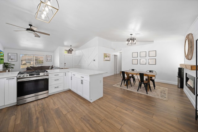 kitchen featuring vaulted ceiling, light countertops, stainless steel gas range oven, open floor plan, and ceiling fan with notable chandelier