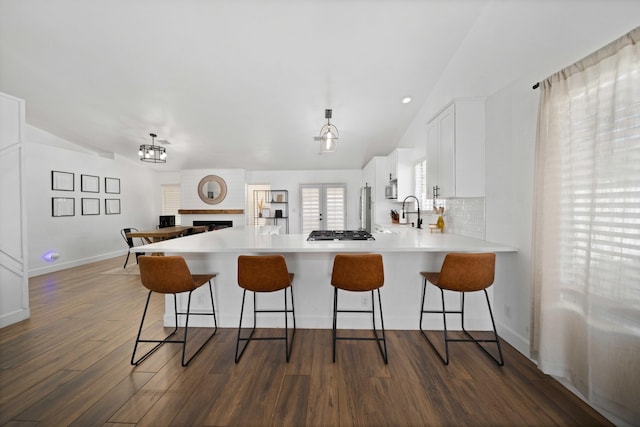 kitchen featuring lofted ceiling, appliances with stainless steel finishes, light countertops, a kitchen bar, and a peninsula