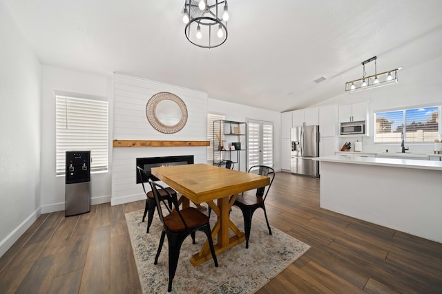 dining area featuring dark wood-style floors, a healthy amount of sunlight, lofted ceiling, and a fireplace