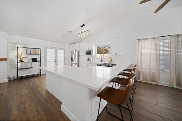 kitchen featuring a sink, stainless steel appliances, vaulted ceiling, light countertops, and white cabinets