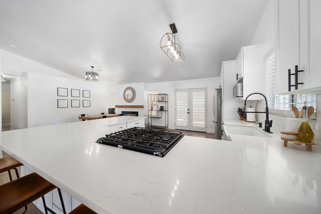 kitchen featuring white cabinets, a sink, appliances with stainless steel finishes, a breakfast bar, and a fireplace
