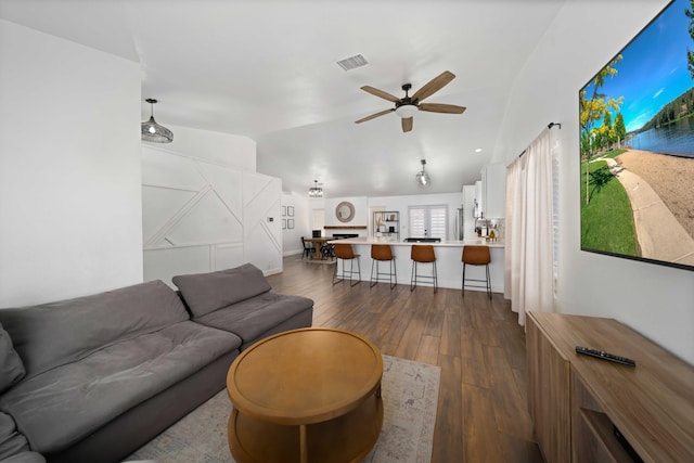 living area featuring dark wood finished floors, visible vents, ceiling fan, and lofted ceiling