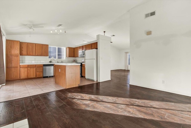 kitchen with high vaulted ceiling, stainless steel appliances, ceiling fan, and a kitchen island