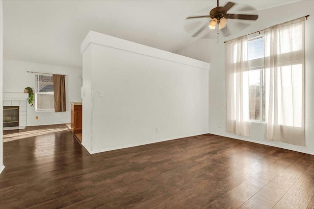 unfurnished room featuring a tile fireplace, lofted ceiling, ceiling fan, and dark hardwood / wood-style flooring