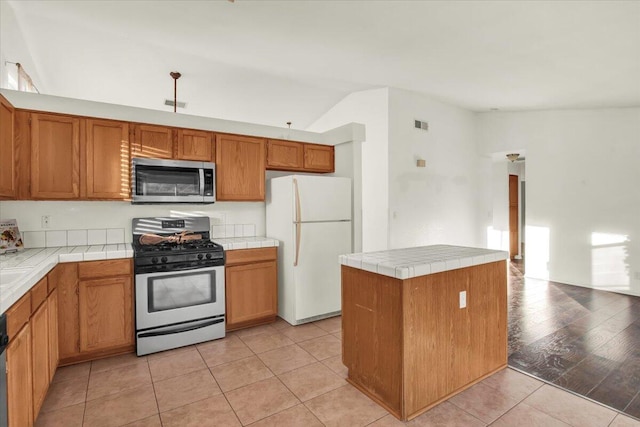 kitchen featuring vaulted ceiling, appliances with stainless steel finishes, and light tile patterned floors