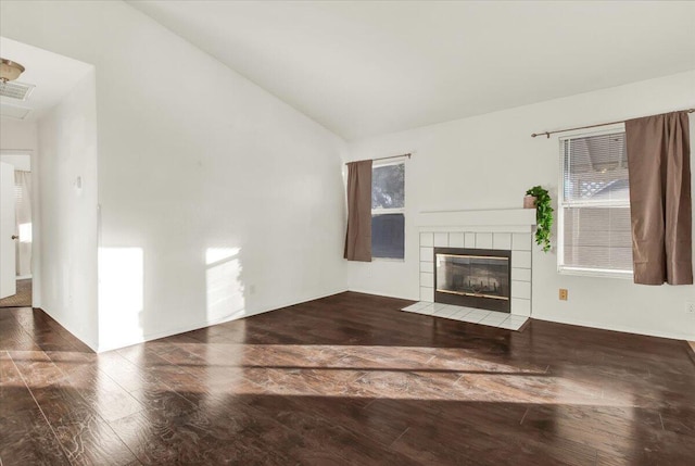 unfurnished living room featuring a tile fireplace, lofted ceiling, and wood-type flooring