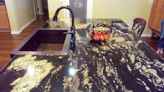 interior details featuring dark stone countertops, sink, and dark hardwood / wood-style floors