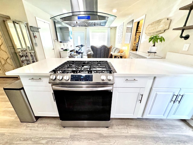 43744 Beech Ave, Lancaster, CA 93534 - kitchen with gas range, island exhaust hood, light wood-style flooring, and white cabinetry