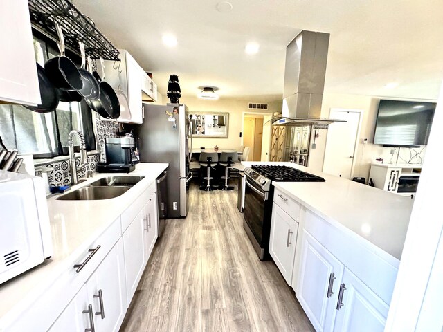 43744 Beech Ave, Lancaster, CA 93534 - kitchen with appliances with stainless steel finishes, island range hood, a sink, light wood finished floors, and white cabinets