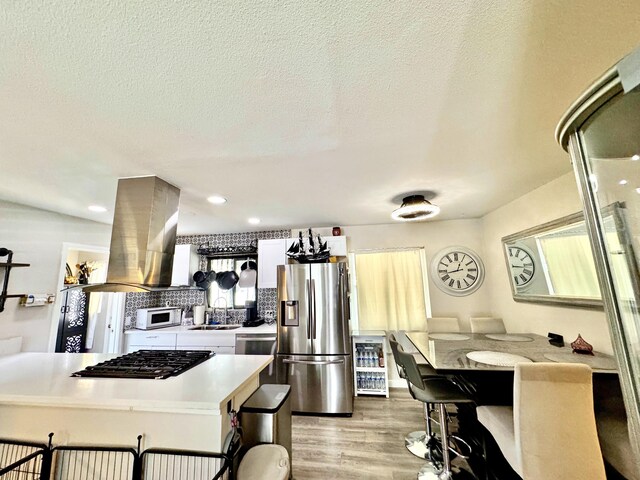 43744 Beech Ave, Lancaster, CA 93534 - kitchen featuring appliances with stainless steel finishes, island exhaust hood, light countertops, light wood-style floors, and a sink