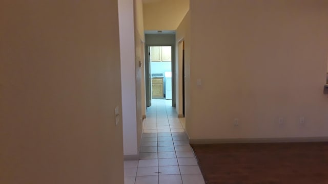 hall with washer / dryer, baseboards, and light tile patterned floors