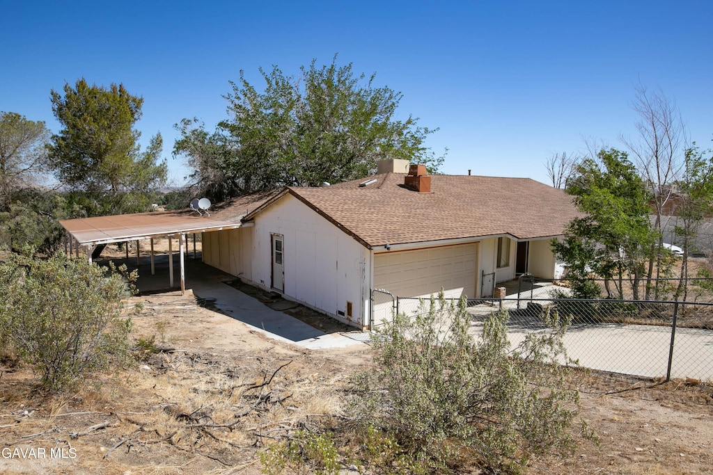 17613 Lakespring Ave, Lake Los Angeles, CA 93591 - view of front of house featuring a chimney, a garage, roof with shingles, and a carport