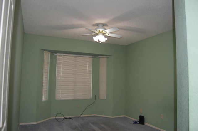 carpeted empty room with a textured ceiling, baseboards, and a ceiling fan