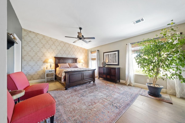 bedroom with baseboards, light wood-type flooring, visible vents, and wallpapered walls