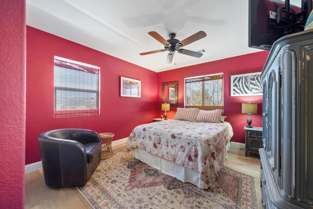 bedroom featuring a wood stove, visible vents, baseboards, and wood finished floors