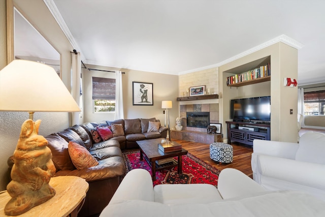 living room featuring built in features, a fireplace, ornamental molding, and wood finished floors