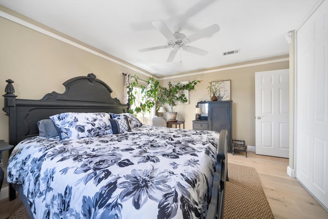 bedroom with baseboards, visible vents, a ceiling fan, ornamental molding, and light wood-type flooring