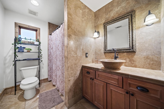 bathroom featuring vanity, toilet, and tile walls