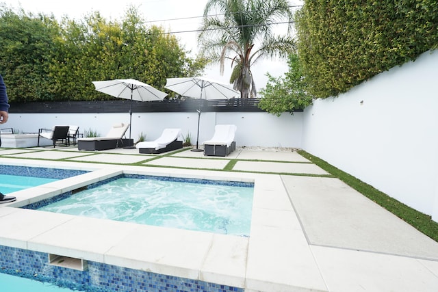 pool with a fenced backyard, a patio, and an in ground hot tub