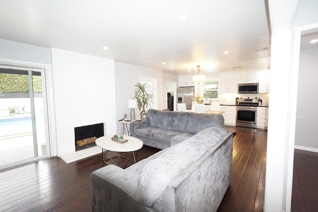 living area featuring a large fireplace, visible vents, dark wood finished floors, and recessed lighting