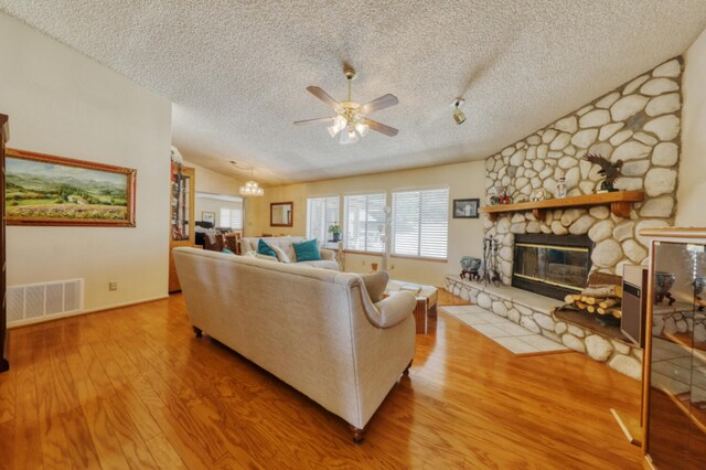 29948 Greenwater Dr, Tehachapi, CA 93561 - living area with a textured ceiling, ceiling fan, wood finished floors, a stone fireplace, and lofted ceiling