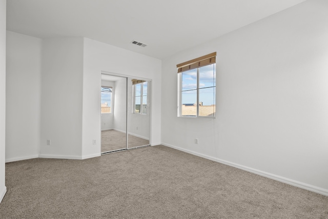 unfurnished bedroom with a closet, carpet flooring, visible vents, and baseboards