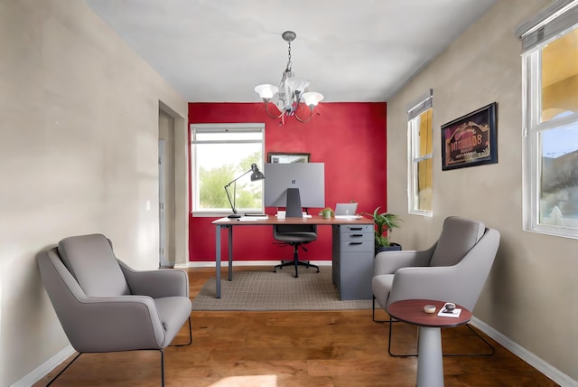 home office featuring an accent wall, baseboards, a notable chandelier, and wood finished floors