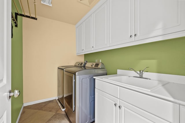 washroom featuring cabinet space, visible vents, washing machine and dryer, a sink, and baseboards