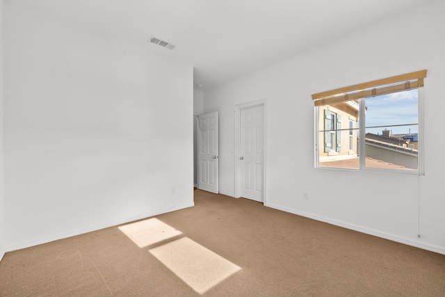 carpeted empty room with visible vents and baseboards