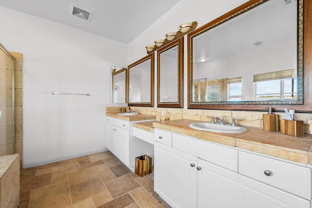 bathroom featuring stone tile flooring, visible vents, a sink, and double vanity