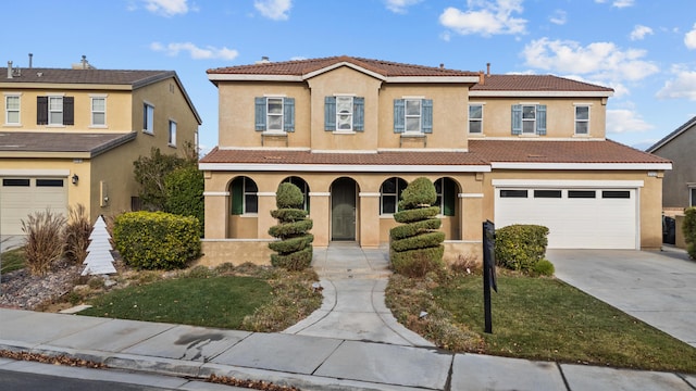 mediterranean / spanish-style home with concrete driveway, a tile roof, an attached garage, and stucco siding