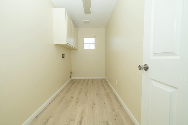 laundry area with hookup for a washing machine, visible vents, light wood-style floors, baseboards, and cabinet space