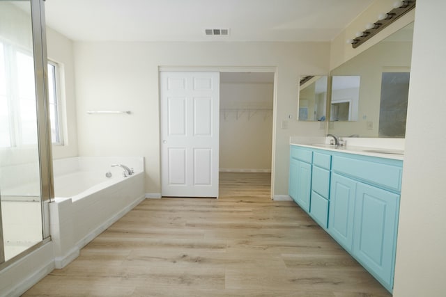 full bath with baseboards, visible vents, wood finished floors, a garden tub, and vanity