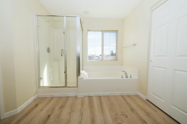 full bath featuring wood finished floors, a garden tub, and a shower stall