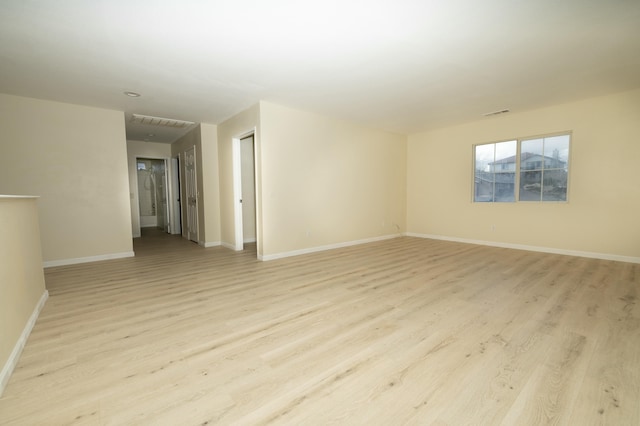 unfurnished room featuring light wood-type flooring, visible vents, and baseboards