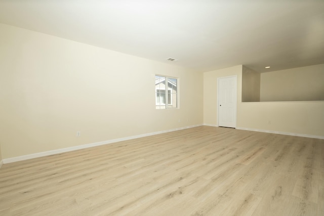 empty room with light wood-type flooring, visible vents, and baseboards