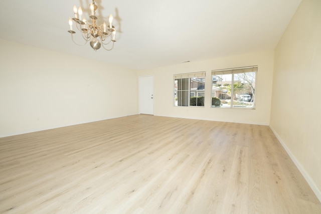 unfurnished room featuring light wood-style floors, baseboards, and an inviting chandelier