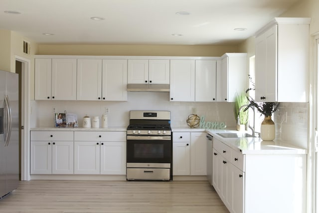 kitchen featuring appliances with stainless steel finishes, a sink, white cabinetry, and under cabinet range hood