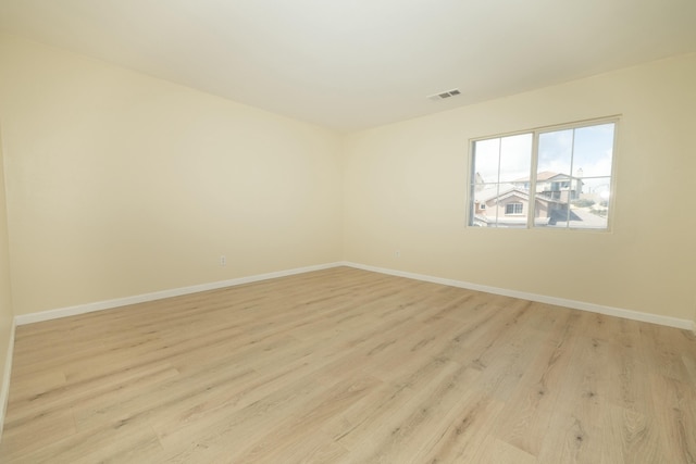 spare room featuring light wood-style flooring, visible vents, and baseboards