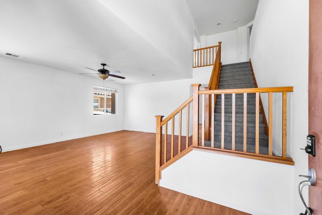 staircase featuring ceiling fan and wood-type flooring