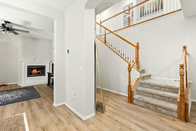 staircase with hardwood / wood-style flooring and ceiling fan