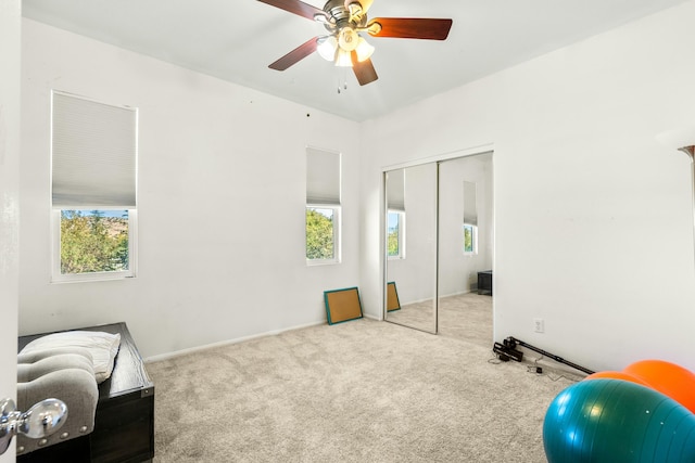 bedroom featuring light colored carpet, a closet, and ceiling fan